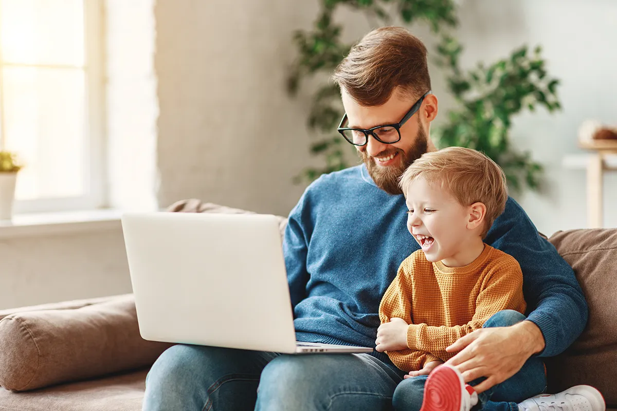 a man and his son using a computer on the sofa