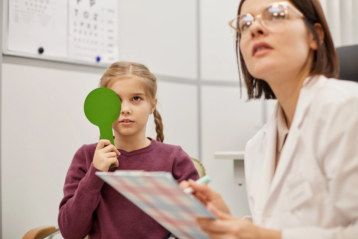Child reading test chart during vision test at optometry office